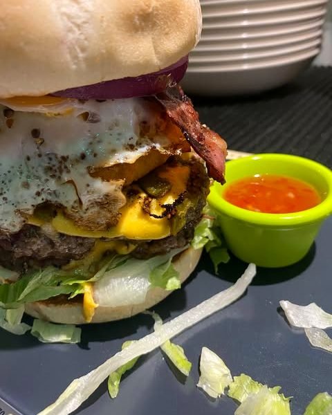 Burger mit geschmolzenem Cheddar, Bacon und Spiegelei, frisch angerichtet.