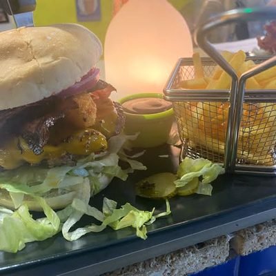 Burger neben einem Drahtkorb mit Pommes.