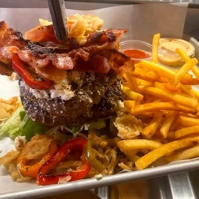 Burger mit Bacon und Pommes auf einem weißen Teller.